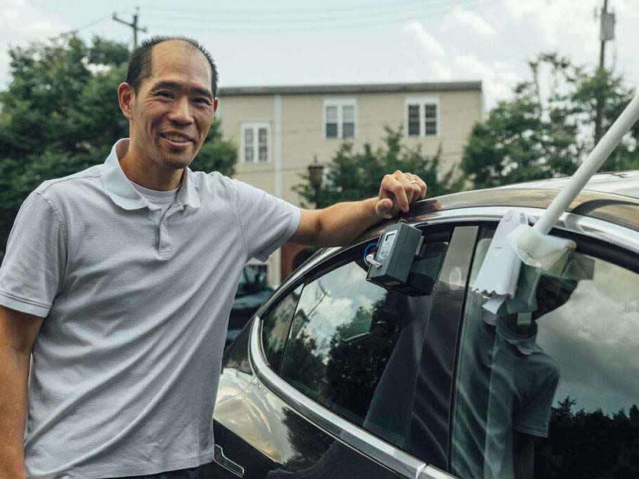 Stephen S. Fong Ph.D. affixes a monitor on his car to measure local ozone pollution.