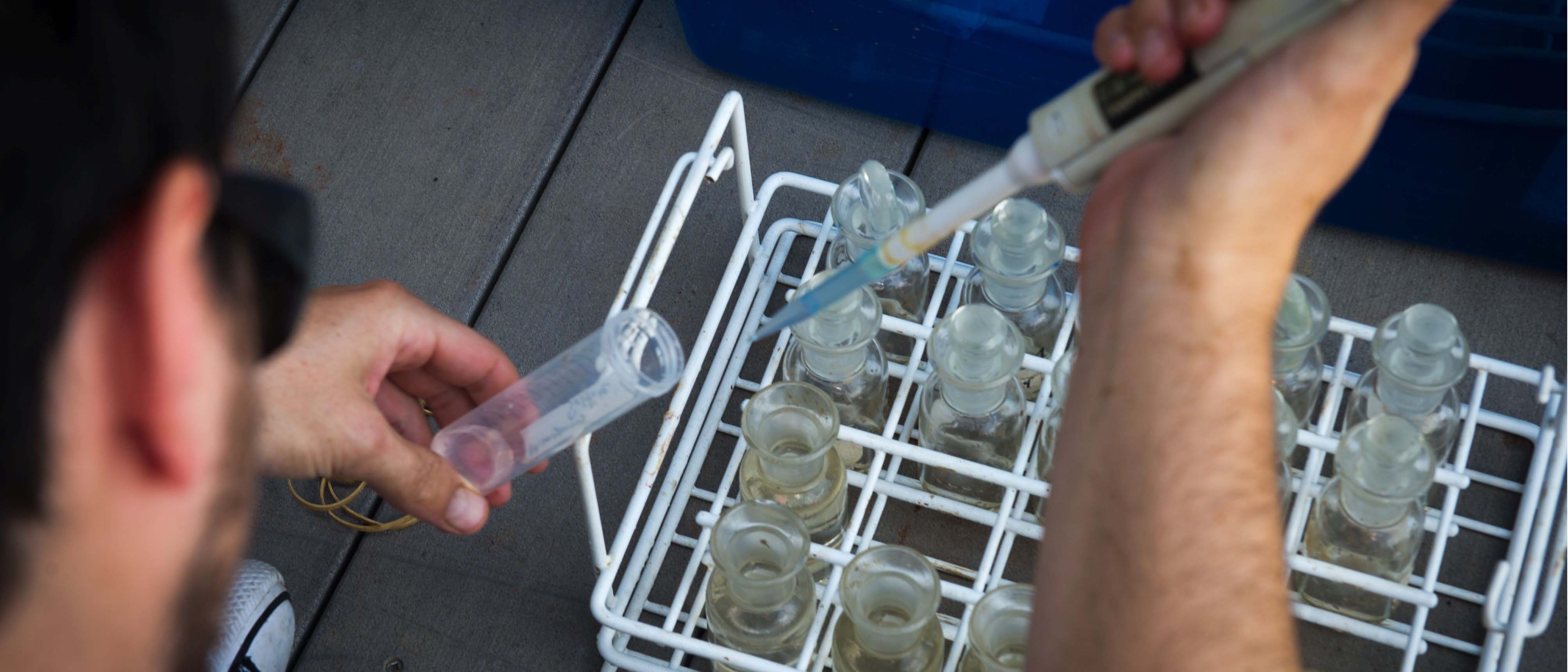 small vials being filled with water from dropper on a pier