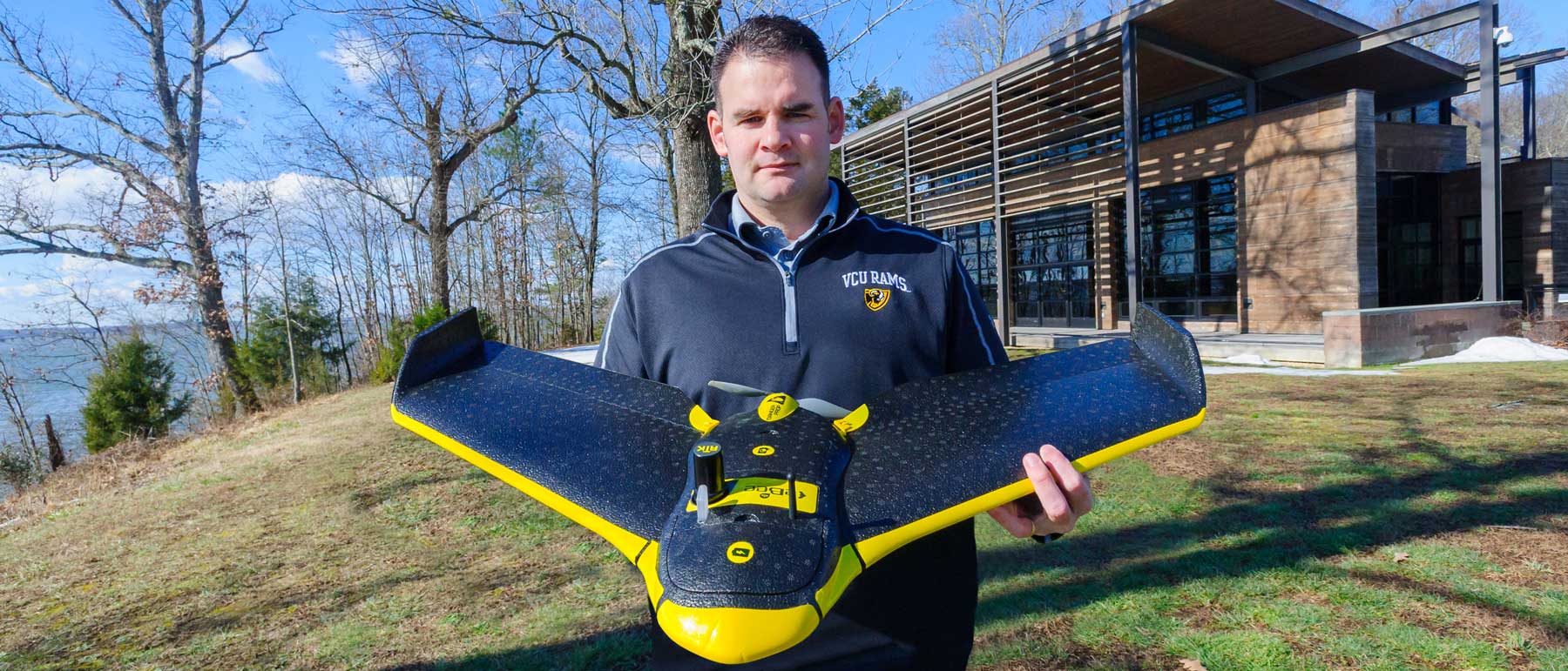 will shuart holding a drone outside the rice rivers center education building