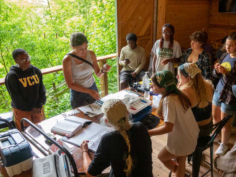 professor teaching a birding class to students in an outdoors classroom