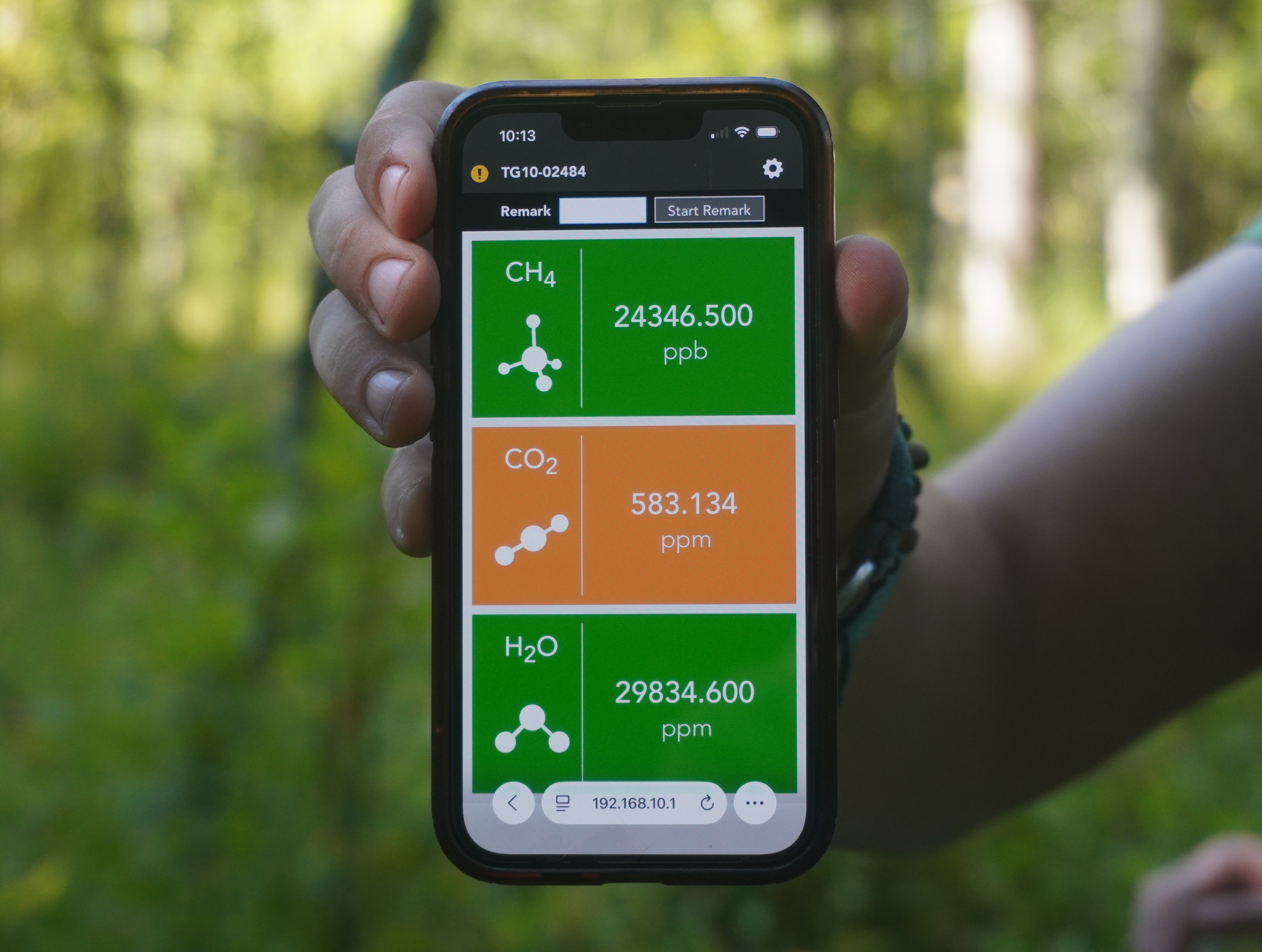A smartphone displaying real-time CO2, CH4, and H2O data.