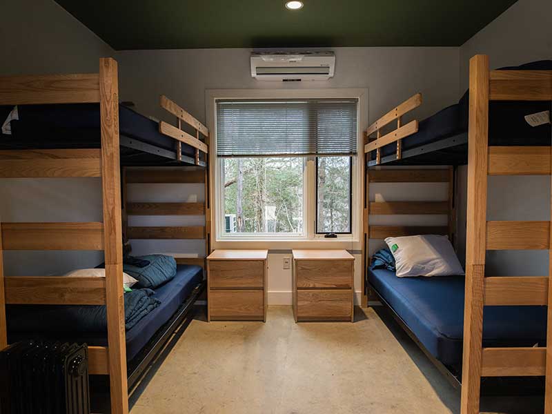 two sets of bunkbeds, two nightstands and a sunny window in a bedroom