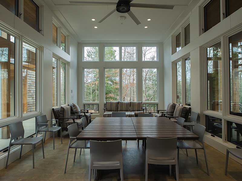 a sunny dining room with lots of windows and chairs around a large table