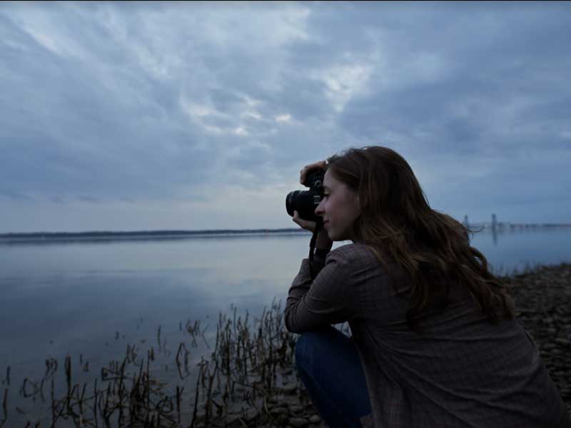 a photographer taking pictures of a body of water at dusk