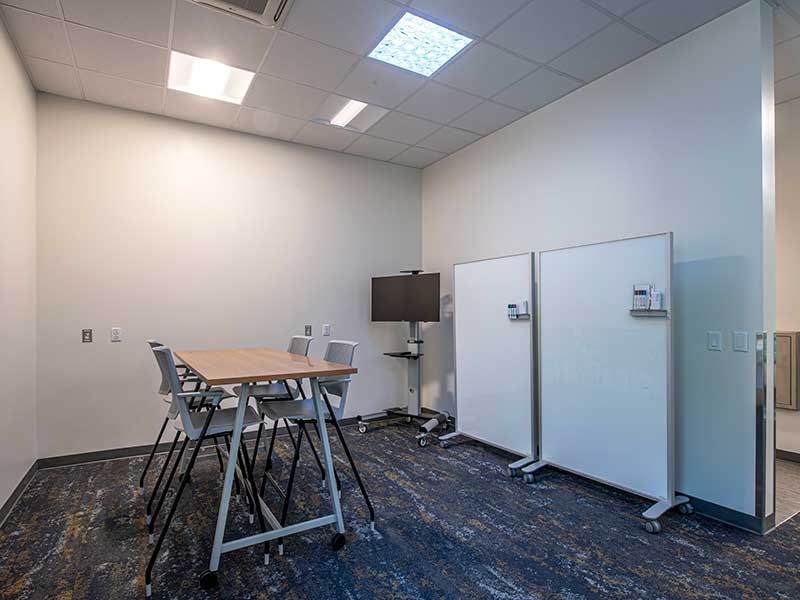 a room with a desk, chairs and whiteboards