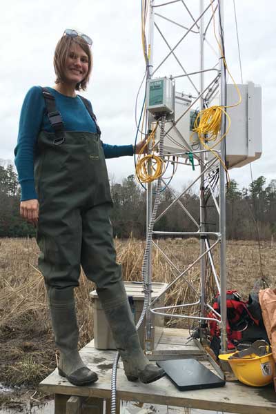 a biologist stands next to an eddy covariance flux tower